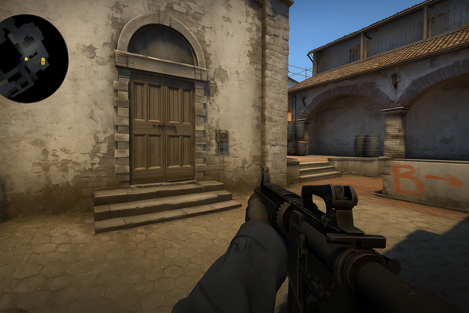 Jugador de CS2 apuntando hacia la entrada del sitio B en mapa clásico con entorno detallado.