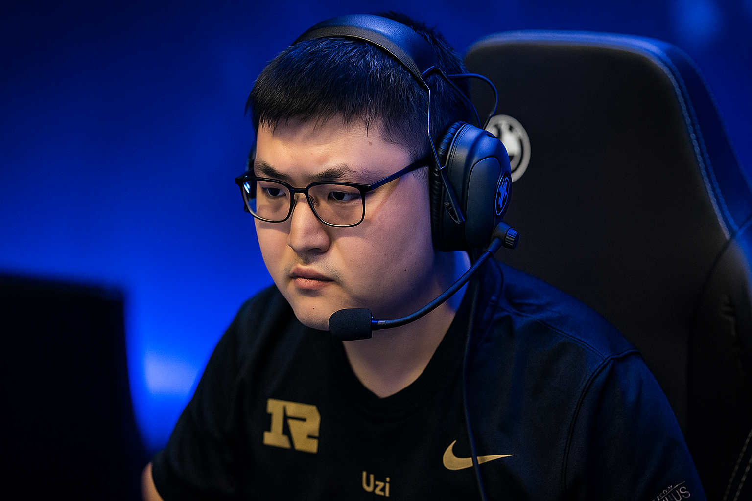Uzi concentrado frente a su pantalla en torneo de LoL con luces azules