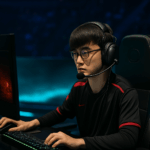 Jugador profesional de esports concentrado en un torneo de League of Legends, frente a su pantalla en un escenario iluminado.