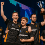 Jugadores de Fnatic celebrando una victoria en el escenario del CS2 Major en Budapest, levantando un trofeo bajo luces naranjas y azules.