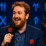 SirActionSlacks hablando entusiasmado en un evento de Dota 2, con símbolos rúnicos azules y ambiente místico en el escenario.