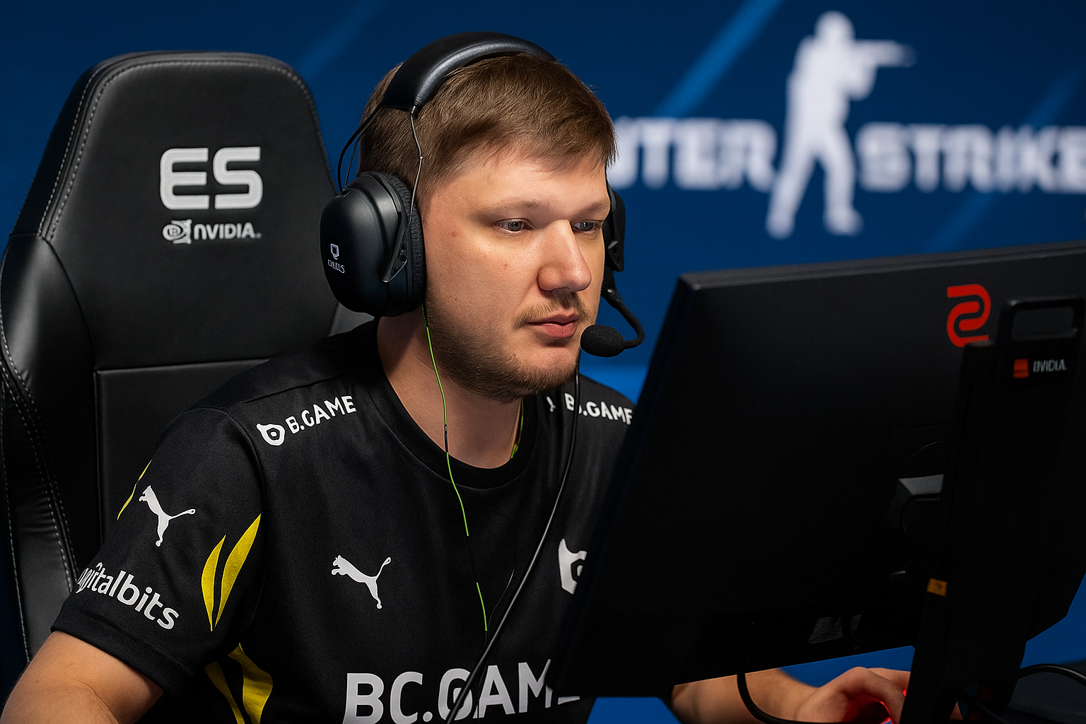 Jugador profesional de CS2 concentrado durante un torneo, frente a su monitor con luces azules de fondo.